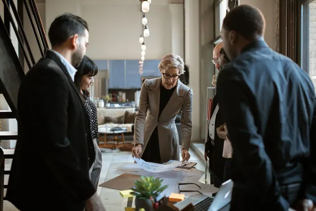 Business team engaged in a collaborative meeting around a workspace with documents.