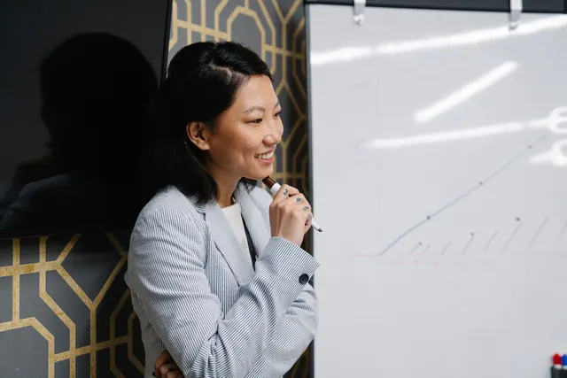 Confident Asian businesswoman presenting with a whiteboard in the office.