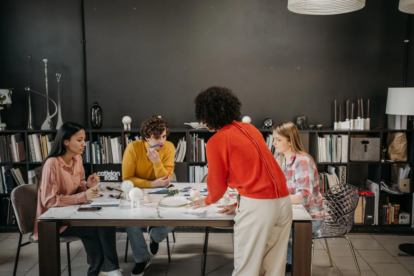 A diverse team engaged in a brainstorming session at a modern office table with documents and ceramics.