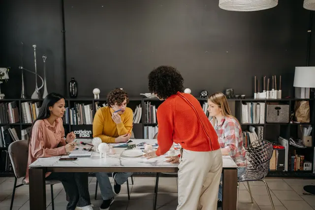 A diverse team engaged in a brainstorming session at a modern office table with documents and ceramics.