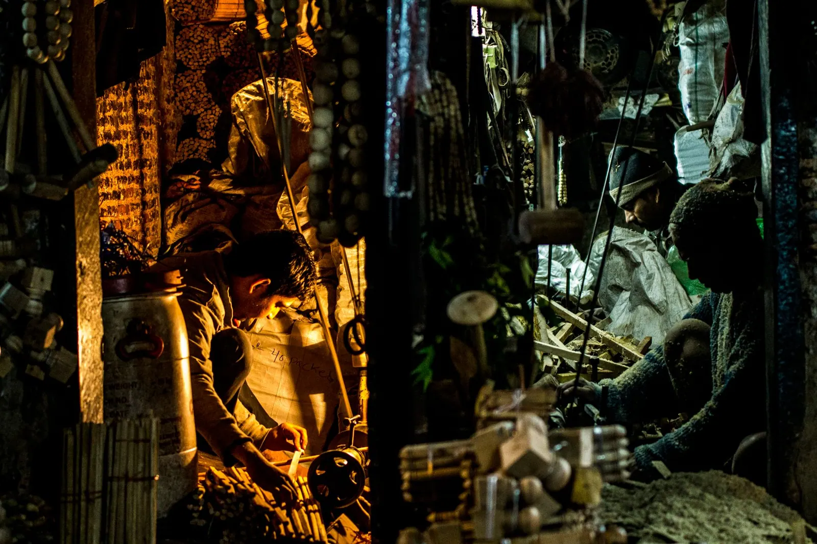 A night view of artisans crafting traditional items in a New Delhi workshop, illuminated by warm light.