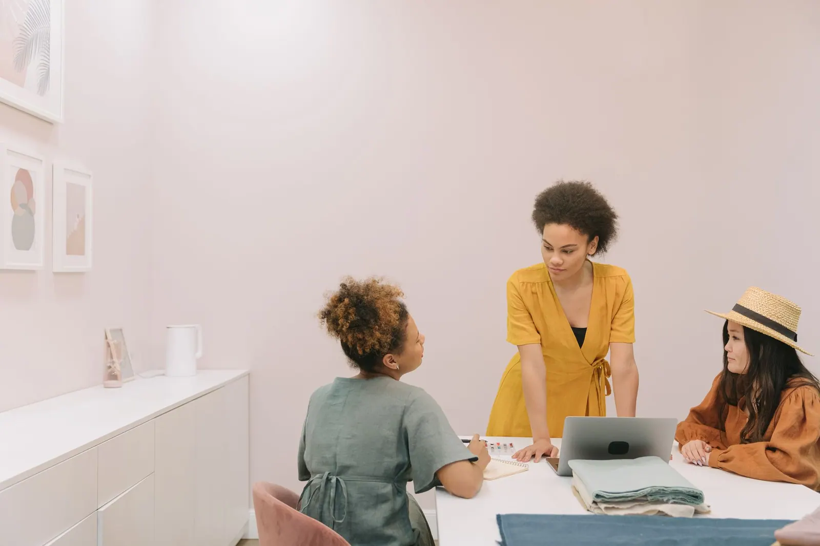 Three diverse women engaged in a collaborative meeting around a table in a stylish office.