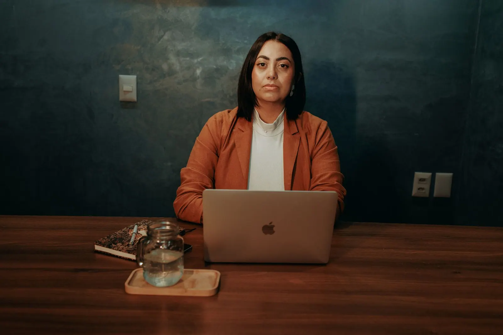 Confident woman in business attire working at a laptop in an office setting.