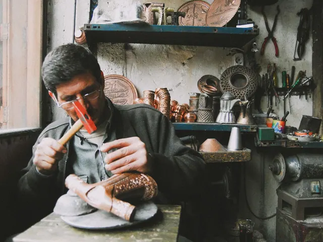 A skilled artisan sculpting copperware with a hammer in a traditional, tool-filled workshop.