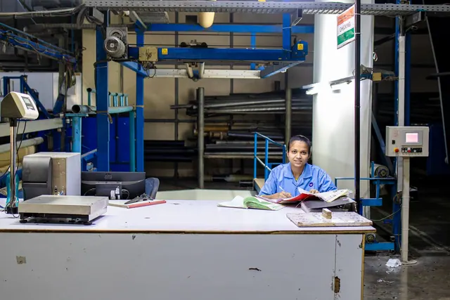Female factory worker at desk in textile plant, overseeing operations.