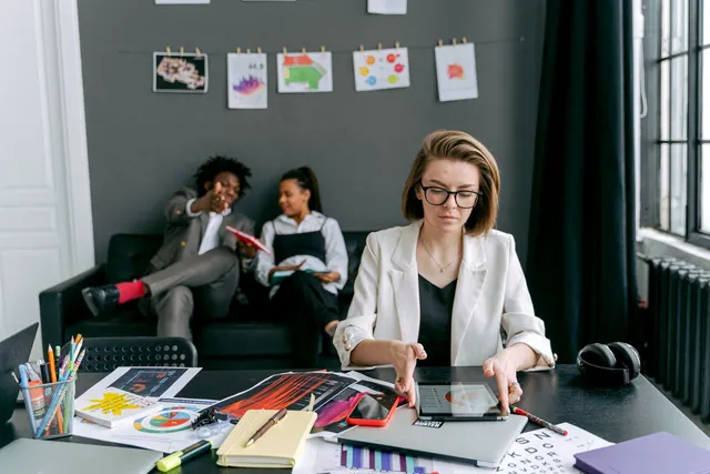 A diverse group working together in a modern office setting with tablets and art on the walls.