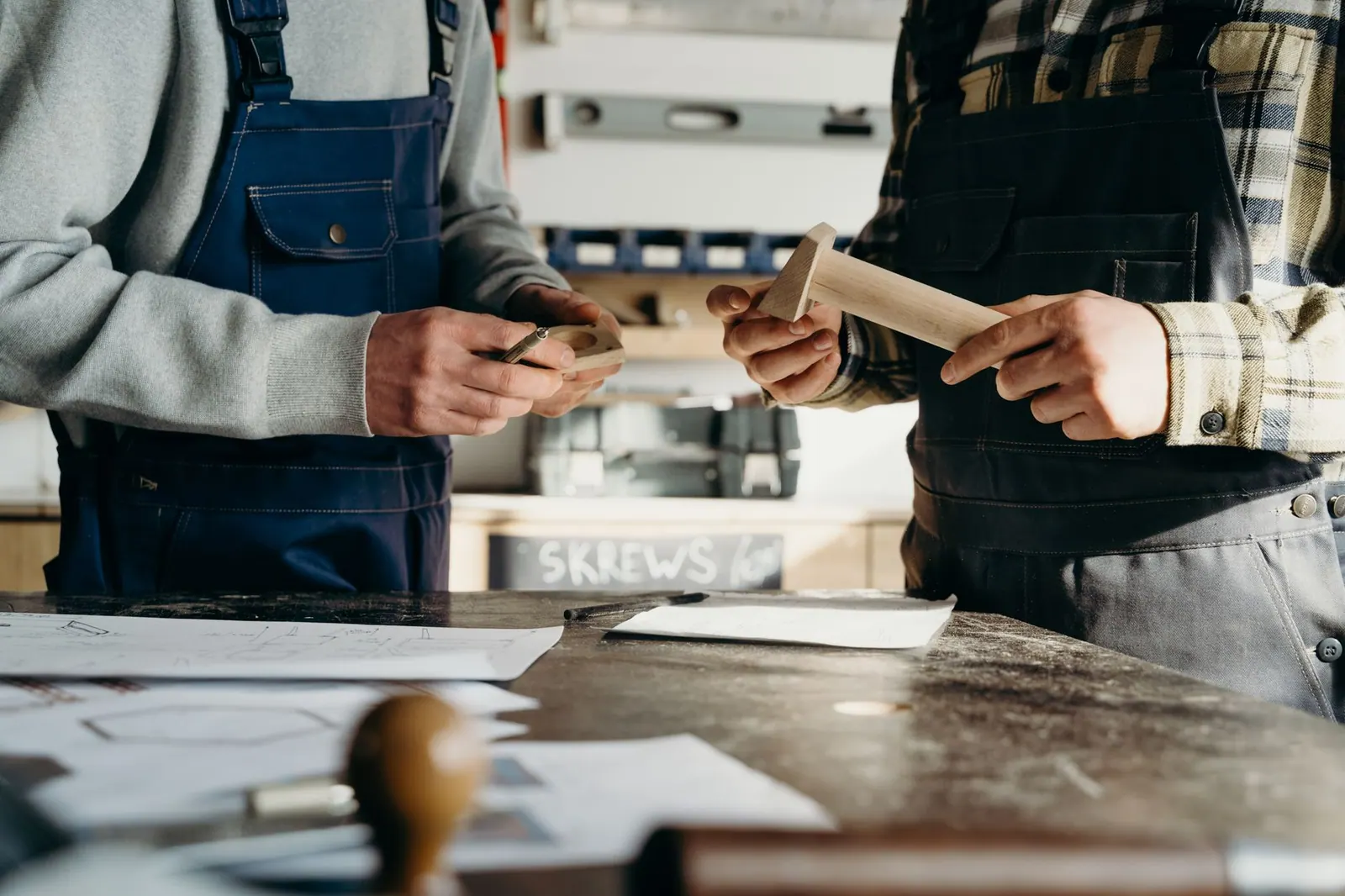 Two craftsmen working on a woodworking project in a well-lit workshop.