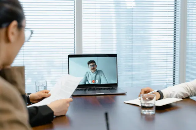 Diverse team in a meeting with remote participant on video call.