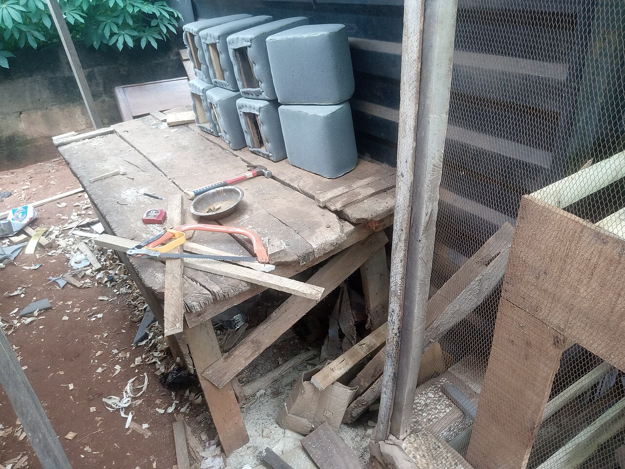 Werkbank mit Säge, Hammer, Holzresten und gepolsterten Stuhlteilen