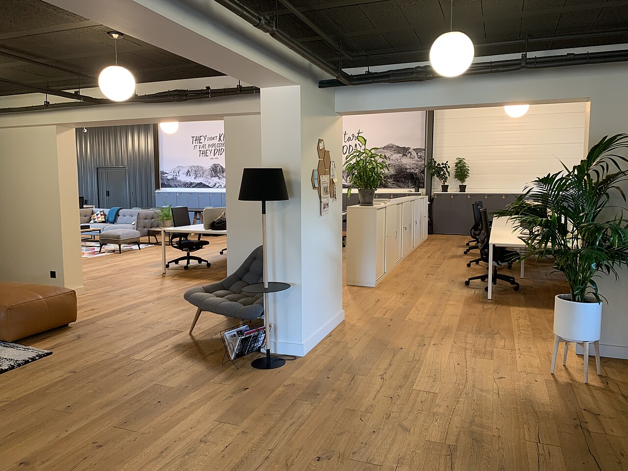 Blick in ein helles offenes Büro mit Holzboden, Pflanzen und Sitzmöbeln