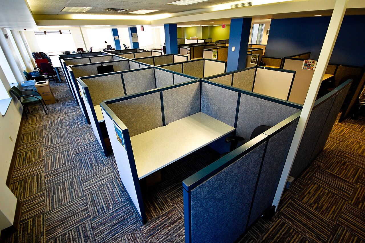 Leeres Großraumbüro mit Cubicle-Arbeitsplätzen und hellem Schreibtisch