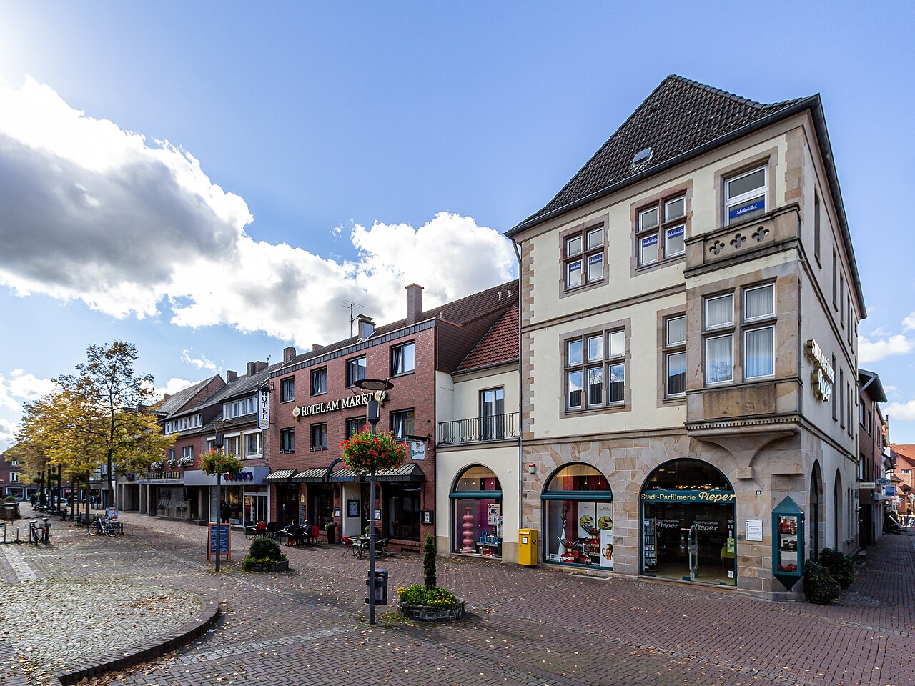Gepflasterter Platz mit Parfümerie, Hotel und Bäumen in Dülmen