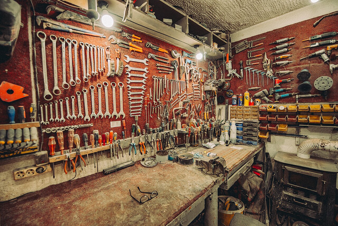 Werkstatt mit vielen Handwerkzeugen an roter Wand und Werkbank im Vordergrund