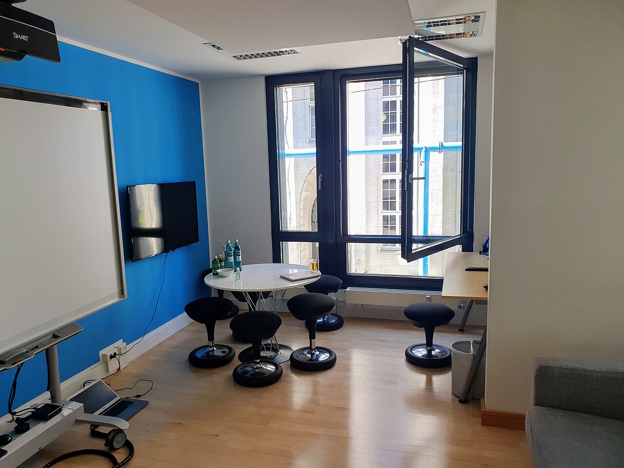 Besprechungsraum mit interaktivem Whiteboard, Bildschirm und rundem Tisch