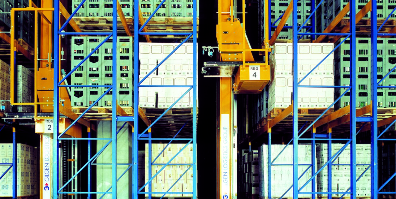 Automatisches Hochregallager mit blauen und gelben Stahlträgern, weißen Kisten und grünen Gitterboxen