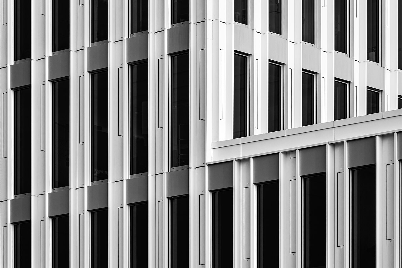 Schwarz-Weiß-Fotografie einer modernen Bürogebäudefassade mit Lamellen und dunklen Fenstern