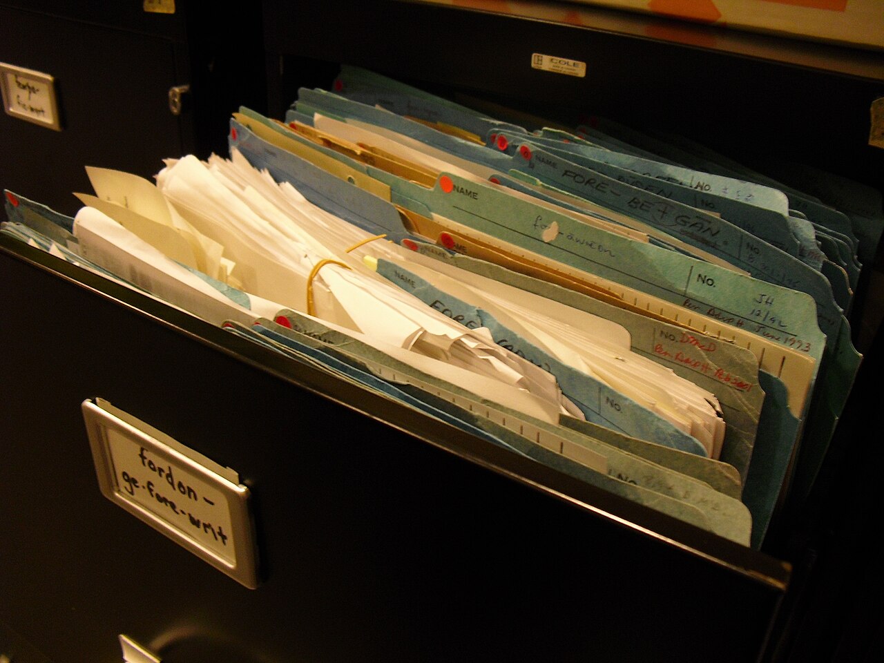 Offene Aktenschublade mit beschrifteten Mappen und Papierunterlagen