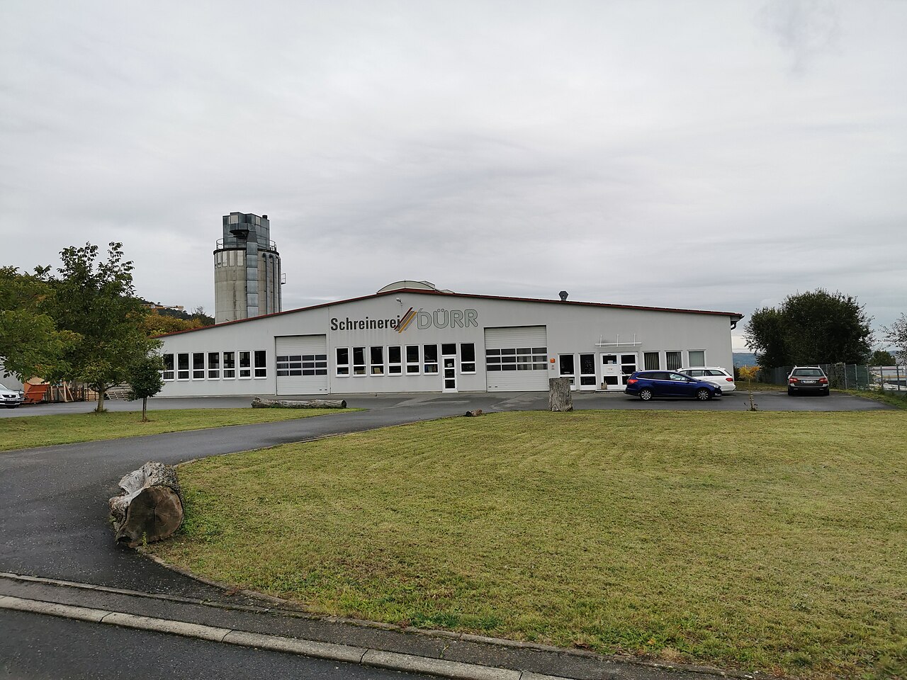 Außenansicht der Schreinerei Dürr in Tauberbischofsheim mit Werkstattgebäude, Sektionaltoren und Silo